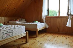 two beds in a room with wooden floors and windows at Beibuki in Naujene