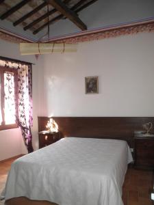 a bedroom with a white bed and a window at Palazzetto Leonardi in San Polo dei Cavalieri