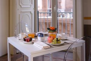 ein weißer Tisch mit Teller mit Lebensmitteln und Früchten darauf in der Unterkunft Napoli Class in Neapel