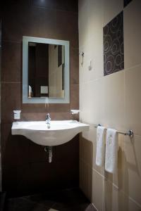 a bathroom with a sink and a mirror and towels at Hotel Victoria in Panagyurishte