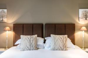 a bedroom with a bed with white sheets and pillows at Carus Green Golf Club Townhouse in Kendal