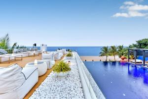 uma piscina com mobiliário branco e a praia em Ace of Hua Hin Resort - SHA PLUS em Cha Am