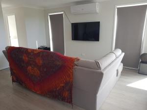 a living room with a white couch and a tv at Hampton Homestay in Palmview