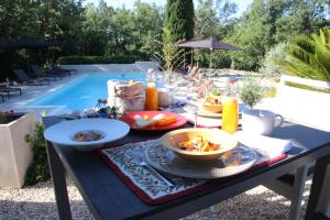 - une table de pique-nique avec de la nourriture à côté de la piscine dans l'établissement Le Hameau Fleur de Pierres , Chambres d'Hôtes , Gite et Restaurant Table d'Hôtes, à Murs