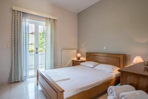 a bedroom with a bed and a sliding glass door at Mystic Garden Apartments in Zakynthos Town