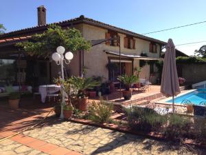 a house with an umbrella and a swimming pool at Annie chambres hôtes in Cassagnabère-Tournas