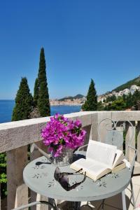 - une table avec un livre et des fleurs sur un balcon dans l'établissement Villa Matilda, à Dubrovnik