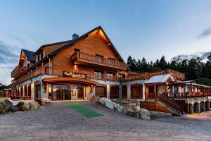 ein großes Holzhaus mit einer Veranda und einem Balkon in der Unterkunft Hotel Restaurant Mont Champ du Feu in Belmont