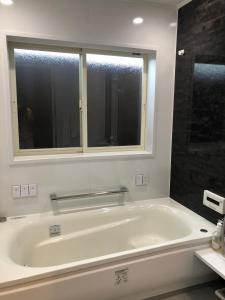 a white bath tub in a bathroom with a window at Guest House "Ro"kumano in Shimonoseki