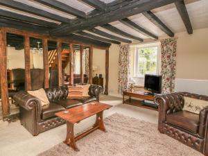 a living room with leather furniture and a tv at Penlone Cottage in Rhayader