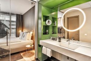 a bathroom with a sink, mirror, and bathtub at H4 Hotel Mönchengladbach im BORUSSIA-PARK in Mönchengladbach