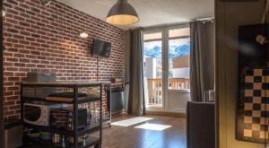 ein Wohnzimmer mit einer Ziegelwand und einem Fenster in der Unterkunft La Roche Blanche in Val Thorens