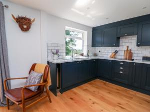 una cocina con armarios azules, una silla y una ventana en Owl Cottage en Llandrindod Wells