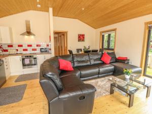 sala de estar con sofá de cuero y mesa en Chale Farm Lodge, en Ventnor