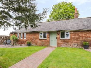 a brick house with a green door and a yard at Berrymoor Cottage in Brampton