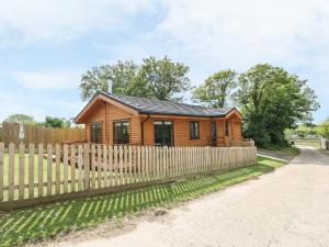 ein Holzhaus hinter einem Zaun in der Unterkunft Chale Farm Lodge in Ventnor