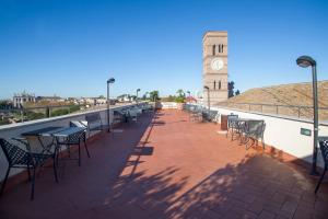 a patio with tables and chairs and a clock tower at Domus Sessoriana in Rome