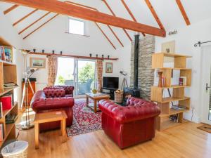 a living room with red leather furniture and a tv at The Barn at Waen y Ffynnon in Ruthin