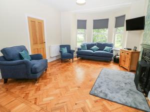 a living room with two blue chairs and a wooden floor at Glyn Ewryd in Bodewryd