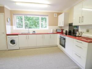 una cocina con armarios blancos y una ventana en Tanglewood, en Colwyn Bay