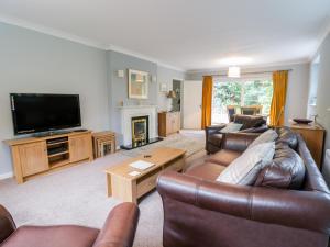 a living room with leather furniture and a flat screen tv at Tanglewood in Colwyn Bay