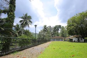 a fence in front of a house with a yard at Kithulgala Rest House in Kitulgala