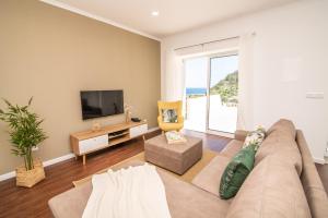 a living room with a couch and a tv at Casa do Outeiro with Heated Pool 30C in Povoação