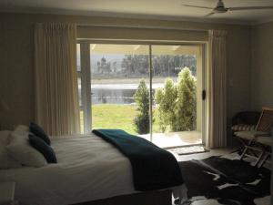 a bedroom with a bed and a large window at Springfontein Wine Estate Stanford River Lodge in Stanford
