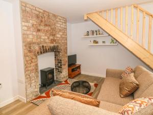 a living room with a brick fireplace and a couch at 1 Tan Y Gerddi in Machynlleth