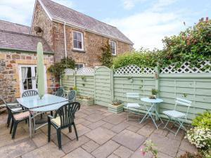 un patio con tavolo, sedie e una recinzione di Castle School House a Kidwelly