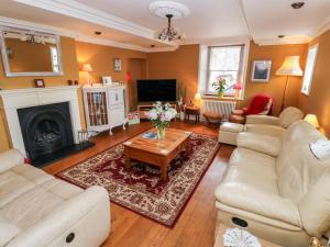 a living room with white furniture and a fireplace at Castle School House in Kidwelly