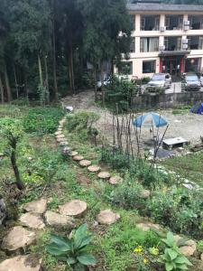 un jardín con rocas y plantas frente a un edificio en Mount Emei Feng Lin Yue Hotel, en Emeishan