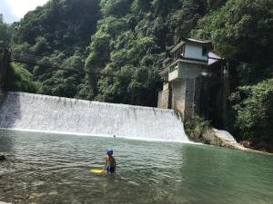un hombre en el agua frente a una cascada en Mount Emei Feng Lin Yue Hotel, en Emeishan