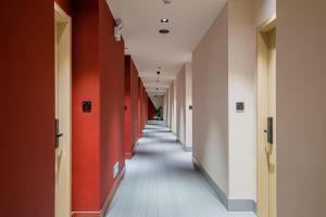 un couloir avec des murs rouges et blancs et un long couloir dans l'établissement PACE HOTEL Suzhou Guanqian Branch, à Suzhou