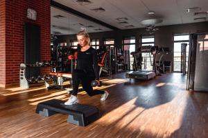 a woman is doing a block in a gym at City Park Hotel & Residence in Poznań