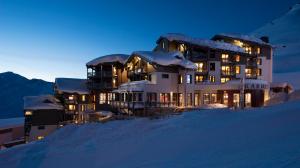 een gebouw bovenop een met sneeuw bedekte heuvel bij Hotel Le Hameau Du Kashmir in Val Thorens