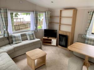 ein Wohnzimmer mit einem Sofa und einem TV in der Unterkunft Brynteg Coastal & Country Retreat in Caernarfon
