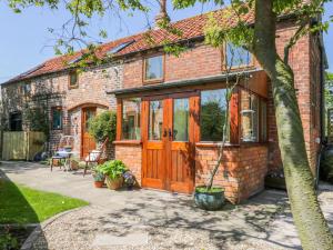 a brick house with wooden doors and a patio at The Stables in Hull