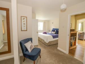 a bedroom with a bed and a blue chair at Daisy Cottage in Tenbury