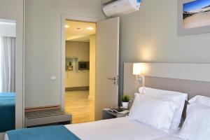 a bedroom with a white bed and a kitchen at Aqualuz Lagos by The Editory in Lagos