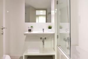 a white bathroom with a sink and a shower at Aqualuz Lagos by The Editory in Lagos