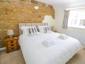 ein Schlafzimmer mit einem weißen Bett mit Ziegelwand in der Unterkunft Treacle Cottage in Warwick