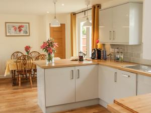 a kitchen with white cabinets and a dining room at Edge View in Church Stretton