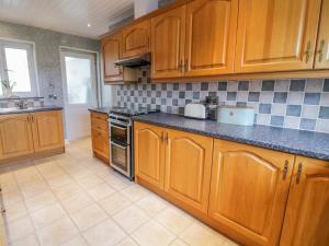 a kitchen with wooden cabinets and a counter top at Pen Bryn in Llanallgo