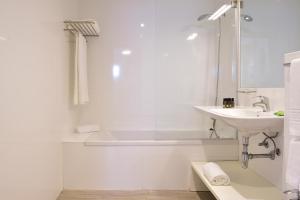 a white bathroom with a sink and a bath tub at Aqualuz Lagos by The Editory in Lagos