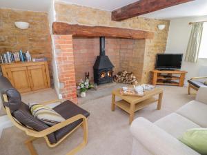 a living room with a fireplace and a couch and chair at Treacle Cottage in Warwick