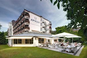 un restaurante con mesas y sombrillas frente a un edificio en Thermenhotel Apollo en Bad Füssing