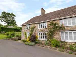 una casa in mattoni con finestre e fiori bianchi di Whitehall Farm Cottage a Honiton