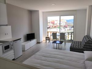 a room with a bed and a living room with a television at Apartamentos Dabarca Combarro in Combarro