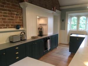 uma cozinha com armários verdes e uma parede de tijolos em Number 6 Narrow Water Castle em Warrenpoint